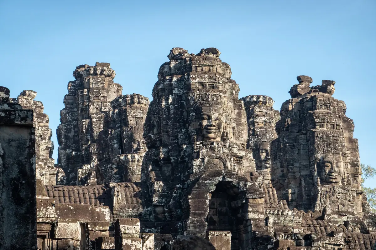 Cluster of stone face towers of the Bayon against a clear blue sky