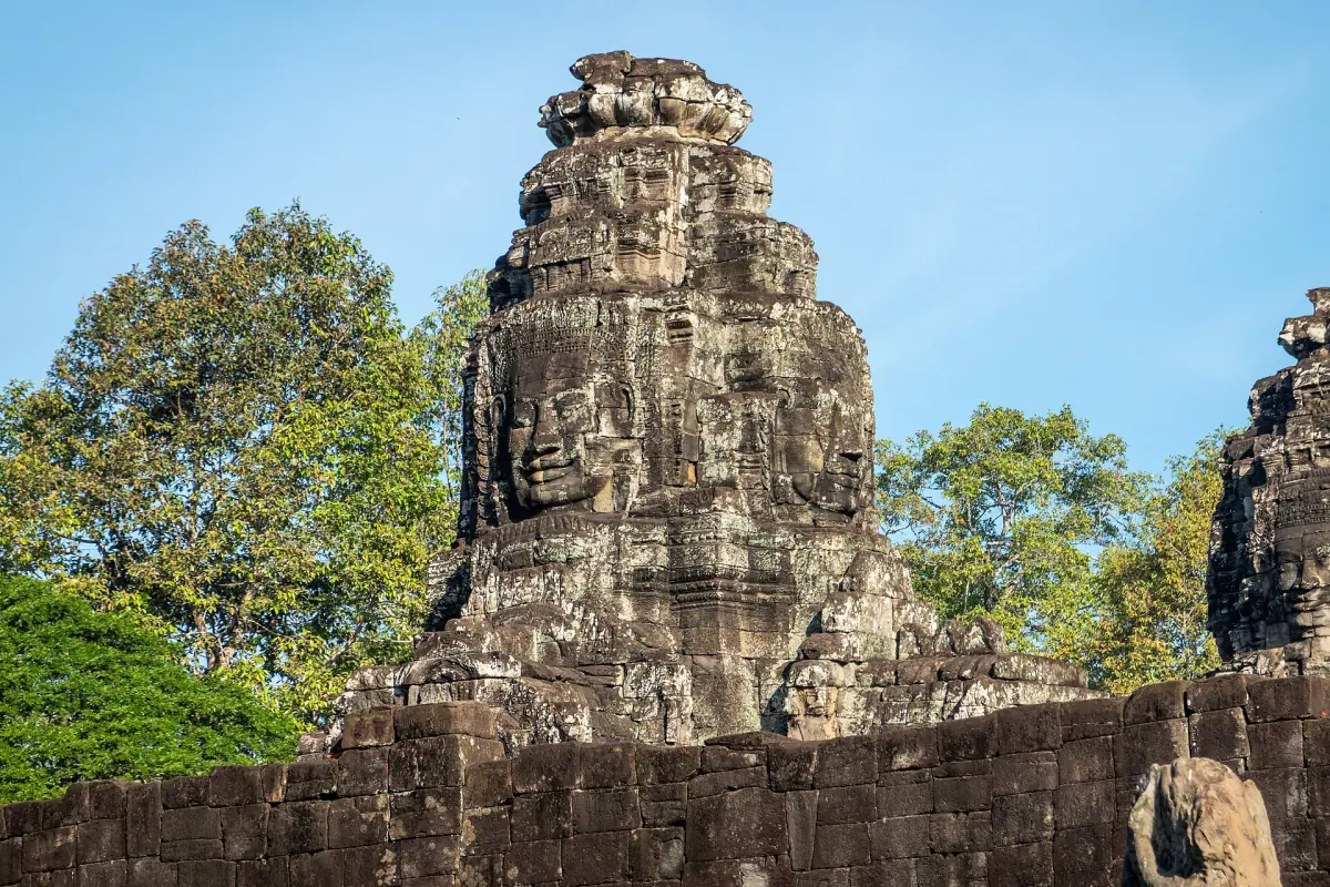 Single stone face tower of the Bayon rising above green trees