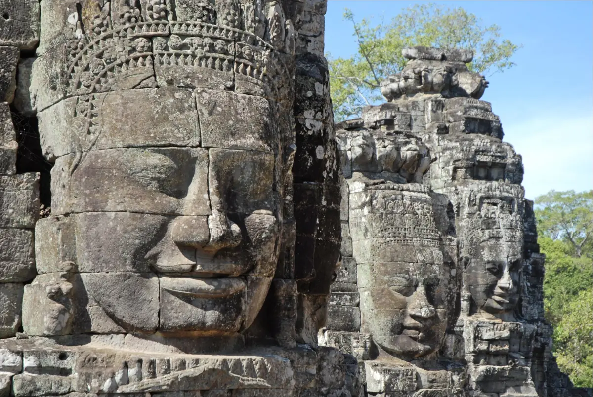 Smiling carved face on a Bayon tower with further towers behind it