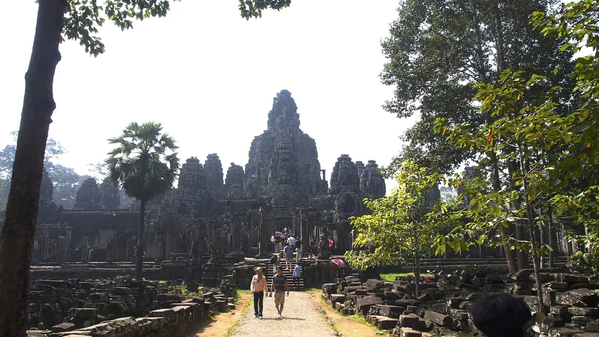 Bayon temple at the end of a path through trees in soft haze