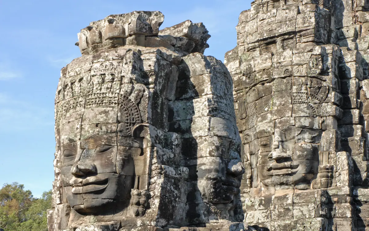 Two large carved faces on neighbouring Bayon towers in bright light