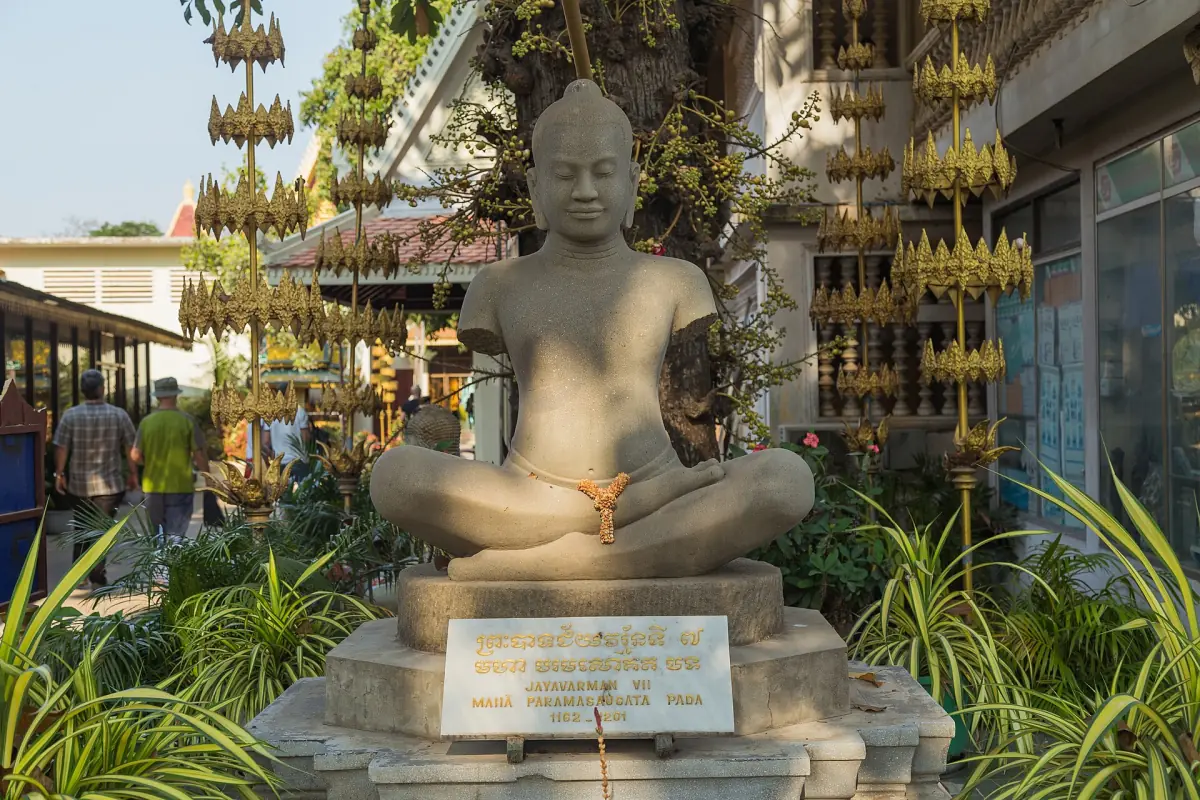 Seated stone statue of a Khmer king in a garden setting