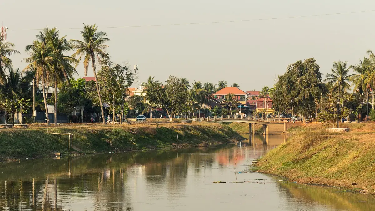 Siem Reap river with palms and a bridge along the bank