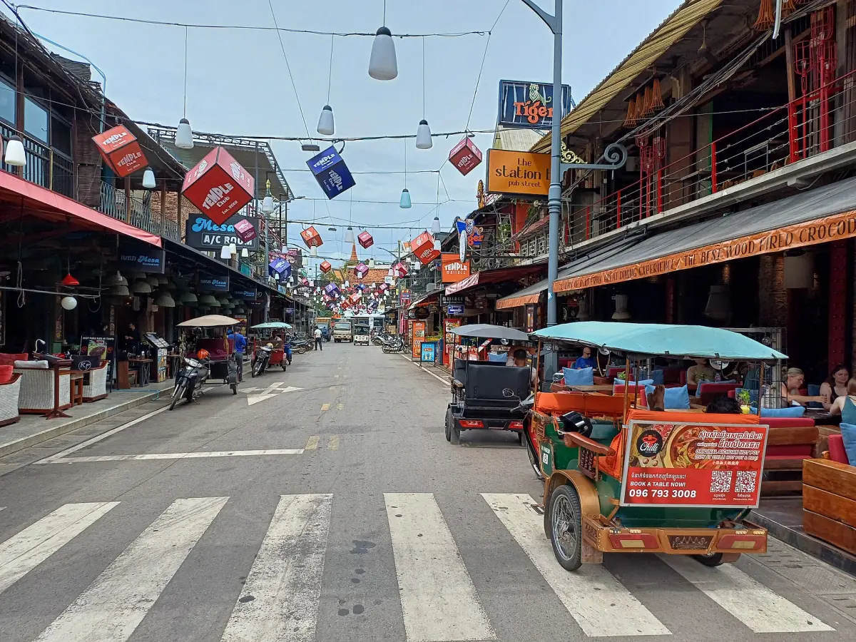 Daytime street in central Siem Reap with tuk-tuks and shops