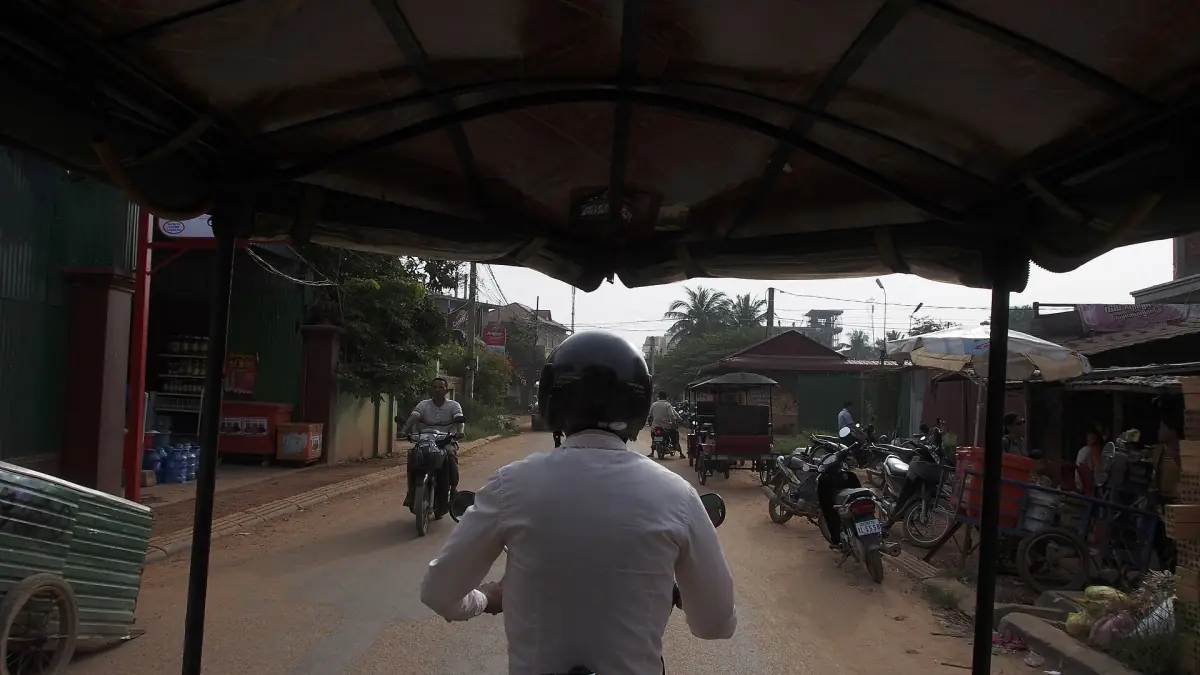 View from a tuk-tuk canopy along a road with motorbikes near Siem Reap